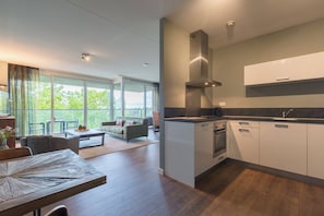Una cocina moderna con armarios blancos, una campana extractora de acero inoxidable y un amplio ventanal con vistas a un balcón.