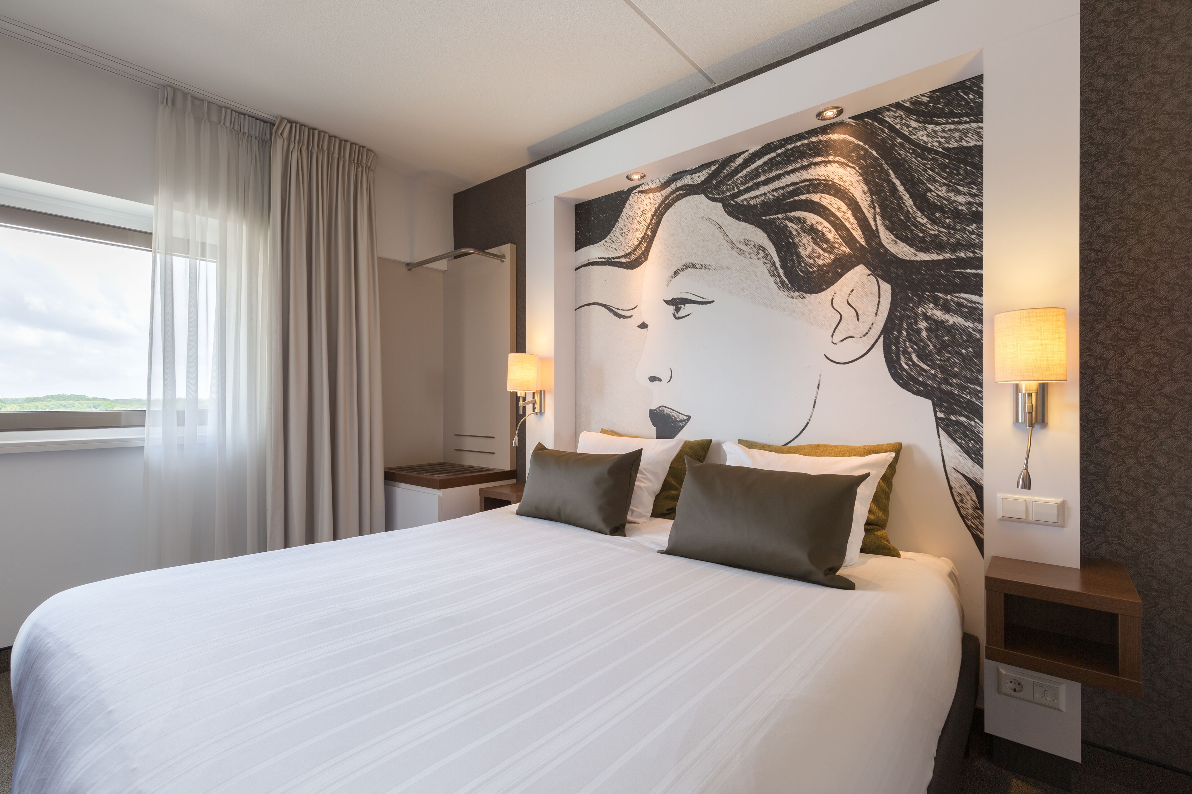 Una habitación de hotel con una cama grande, dos mesitas de noche, un cuadro en la pared y un ventanal con cortinas.