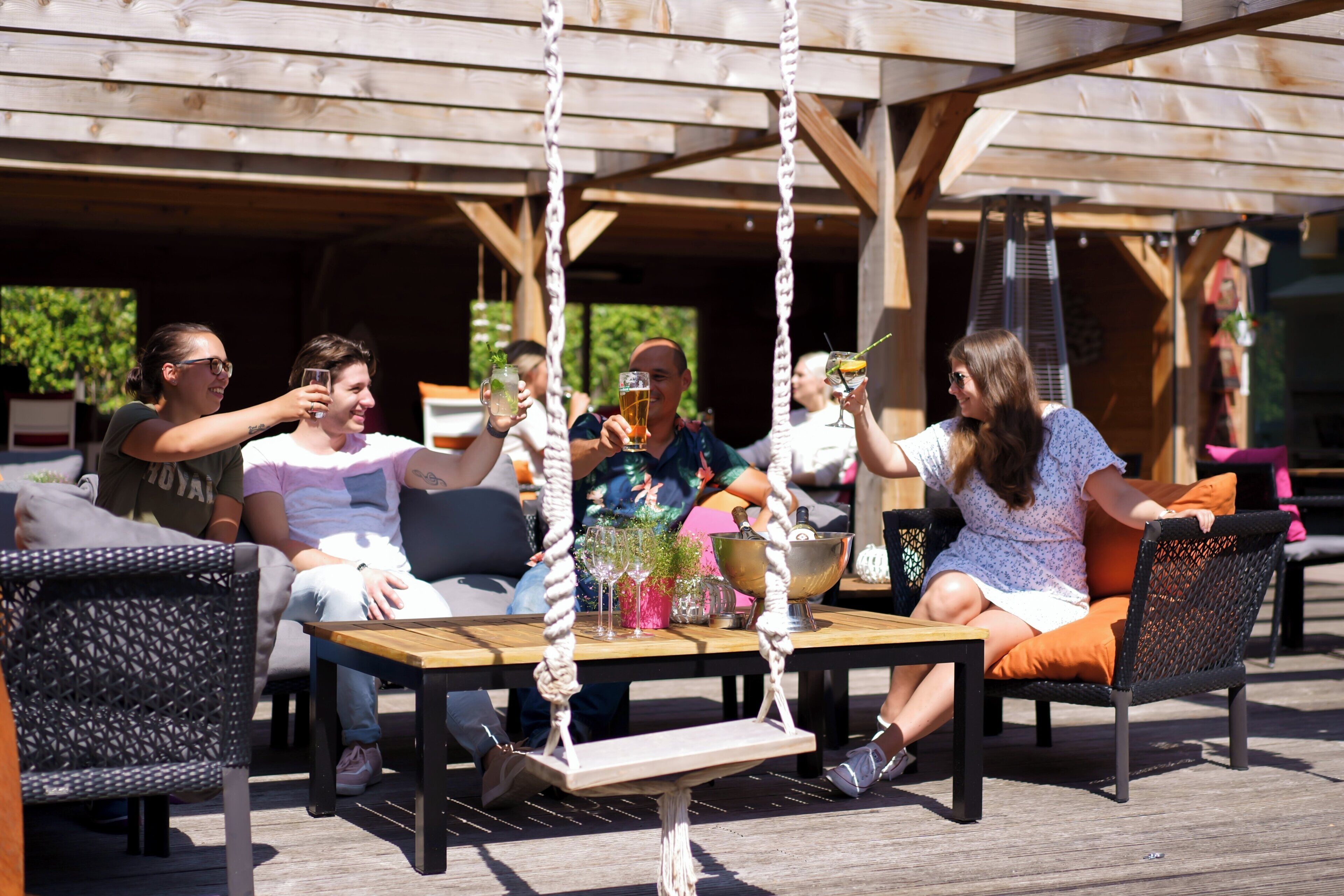 An outdoor seating area with wicker chairs, a wooden table, and a swing.