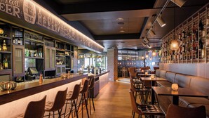 Una zona de bar con taburetes, una barra y estantes llenos de botellas.