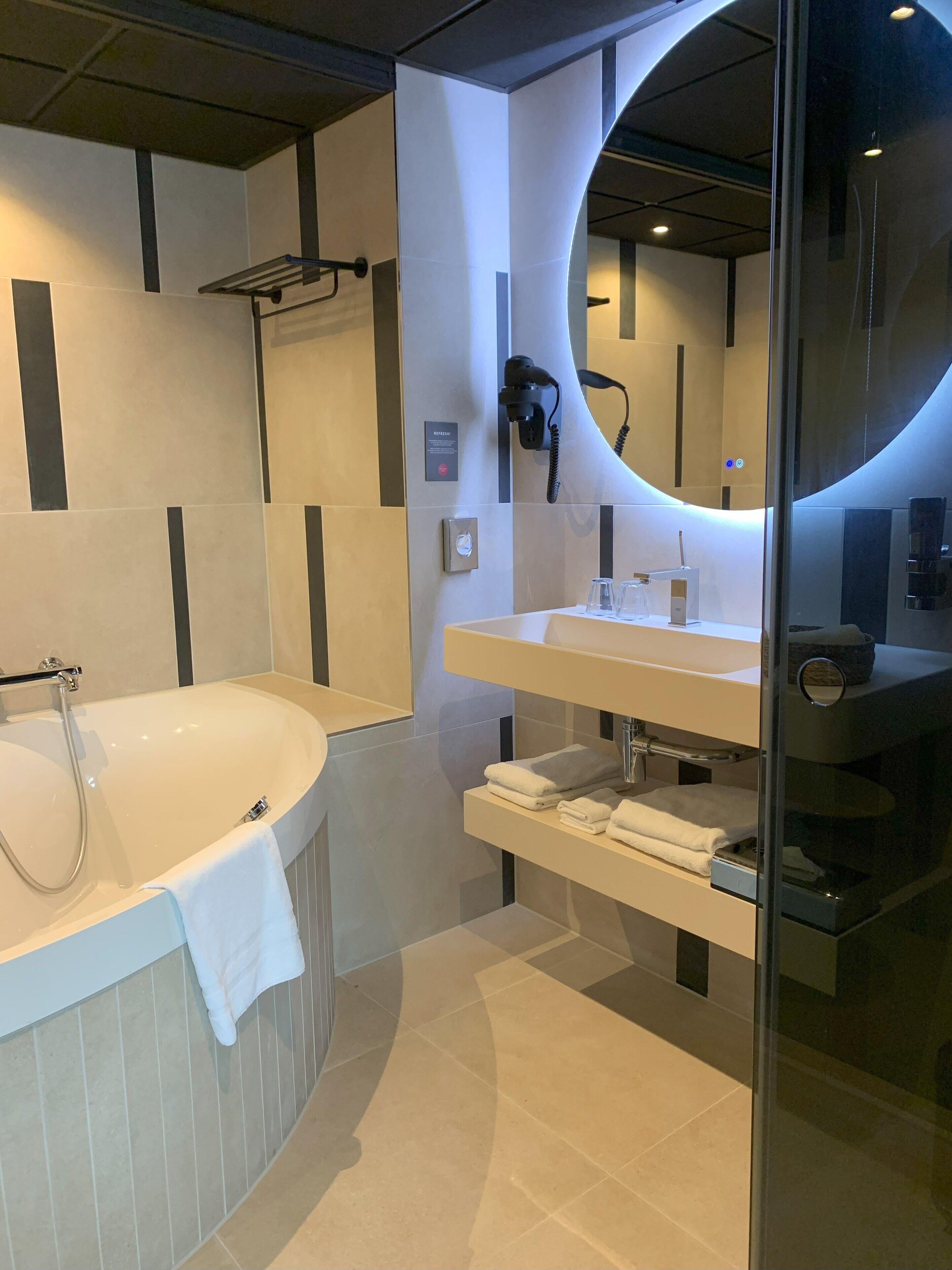 Ein modernes Badezimmer mit freistehender Badewanne, einem Waschtisch mit Spiegel und einer Duschkabine aus Glas.