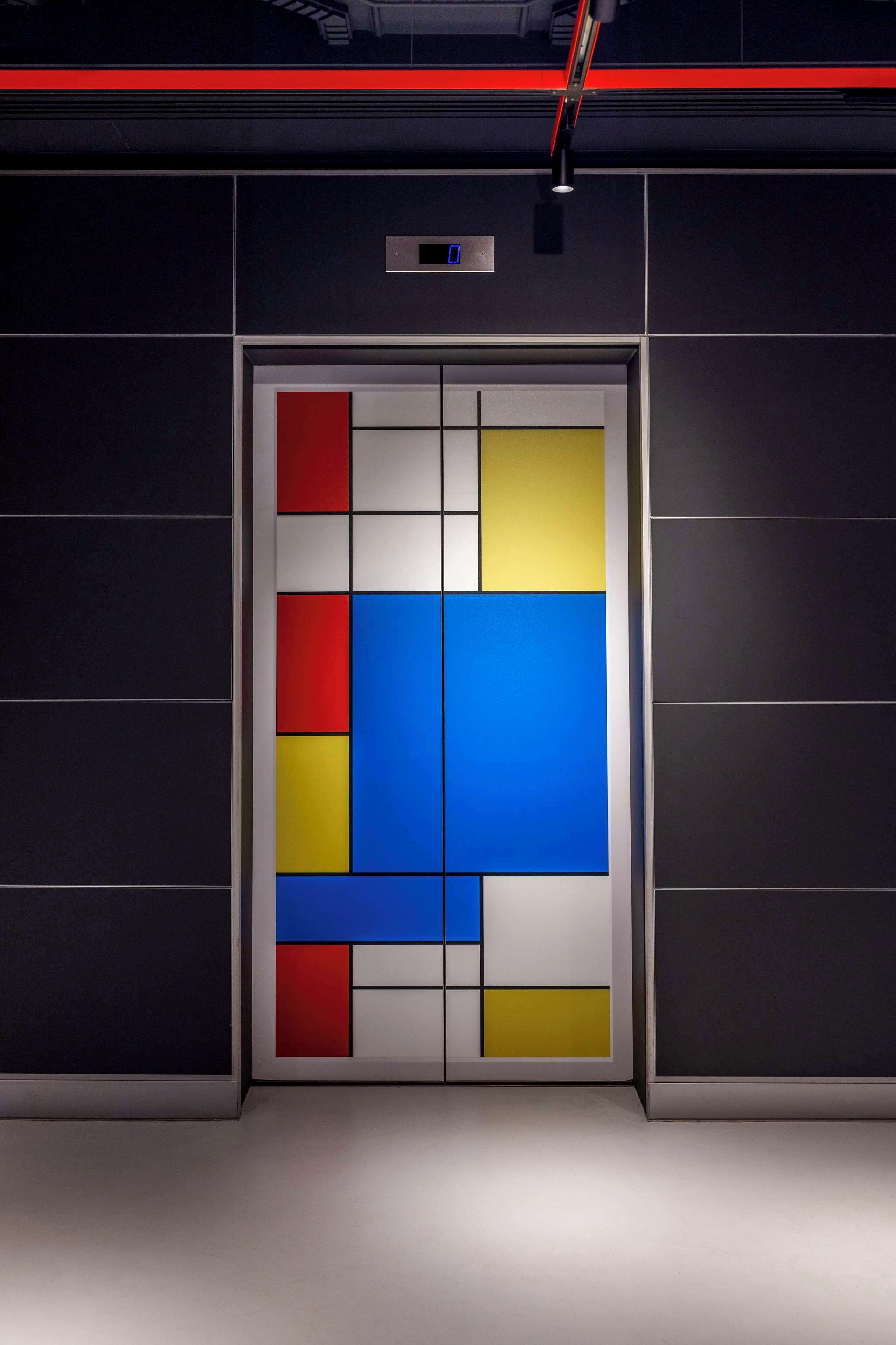 Un ascensor moderno con pantalla digital y puerta de diseño geométrico.