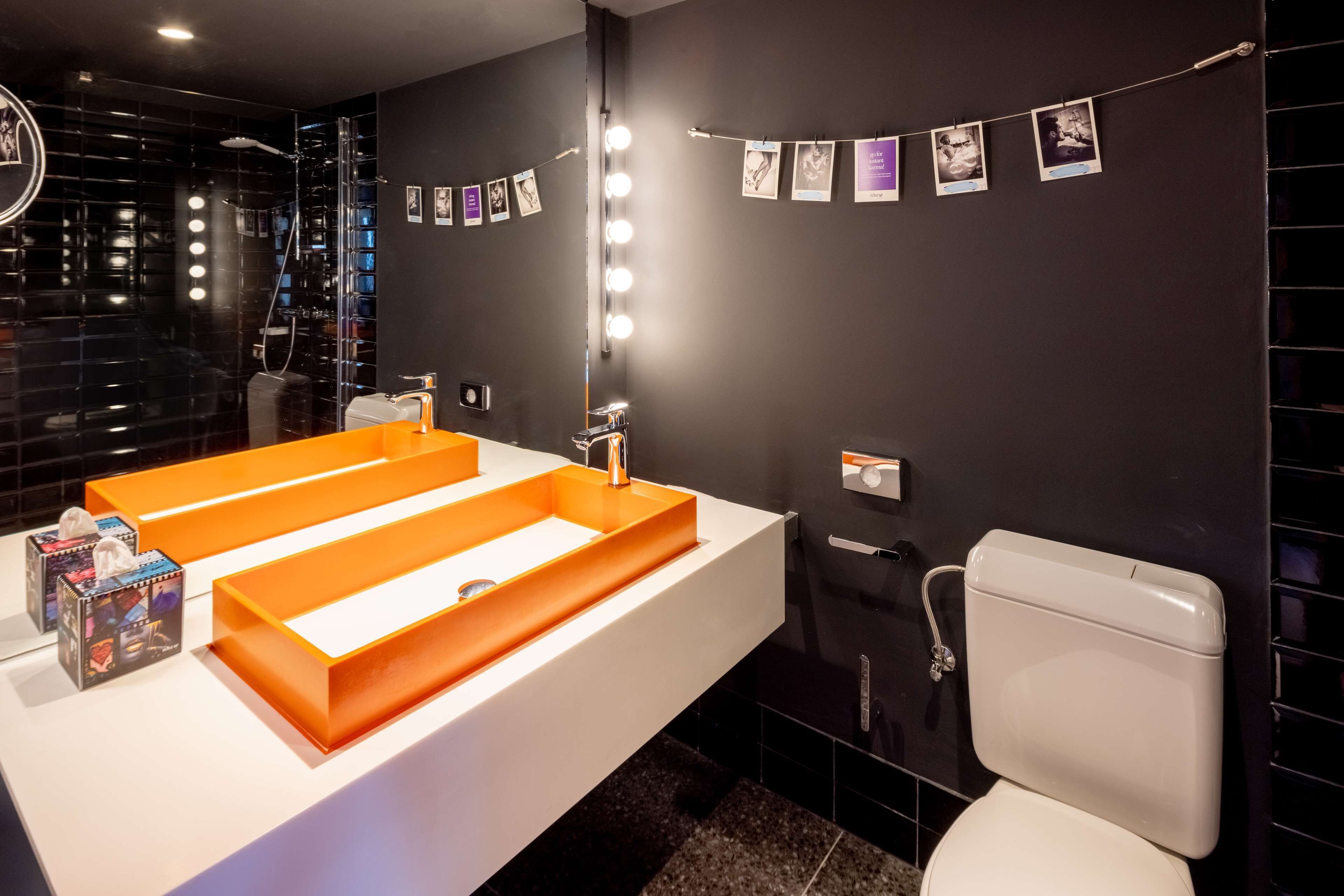Un bany modern amb un gran lavabo blanc, un mirall amb il·luminació i un vàter.