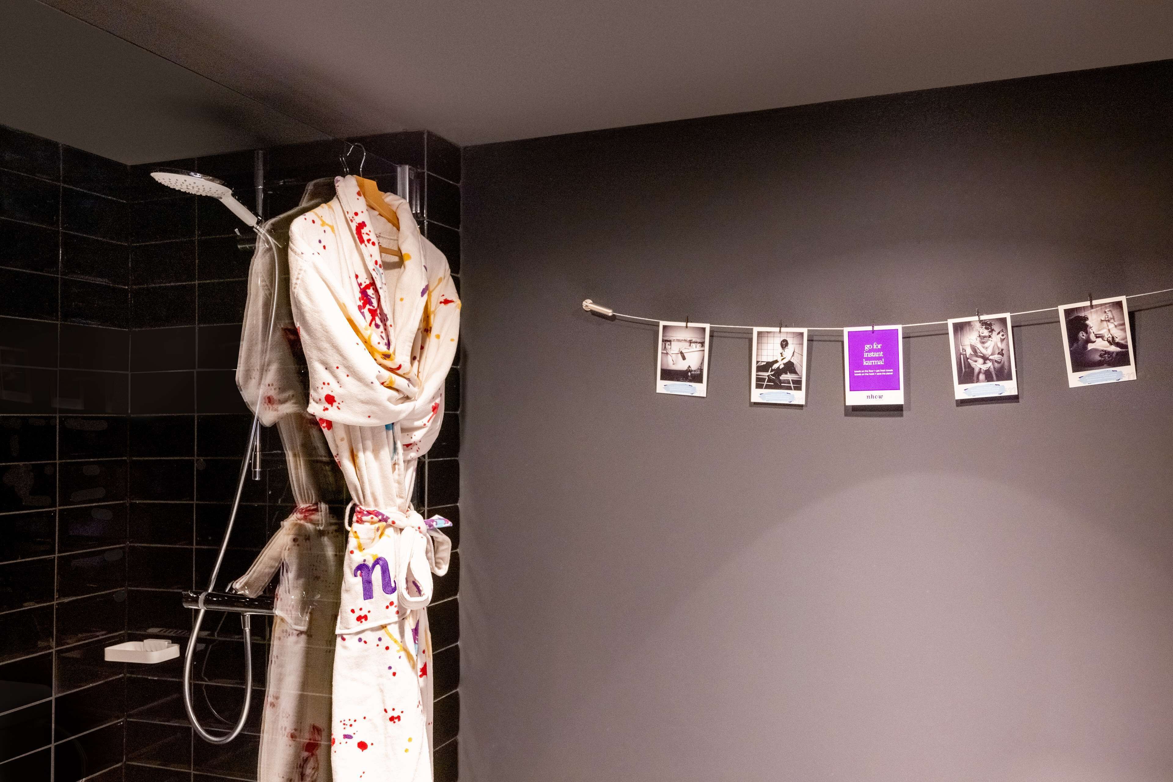 Ein Badezimmer mit Dusche, Handtuchhalter und einer Wand mit mehreren Fotos.