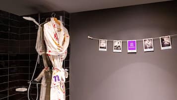 Ein Badezimmer mit Dusche, Handtuchhalter und einer Wand mit mehreren Fotos.