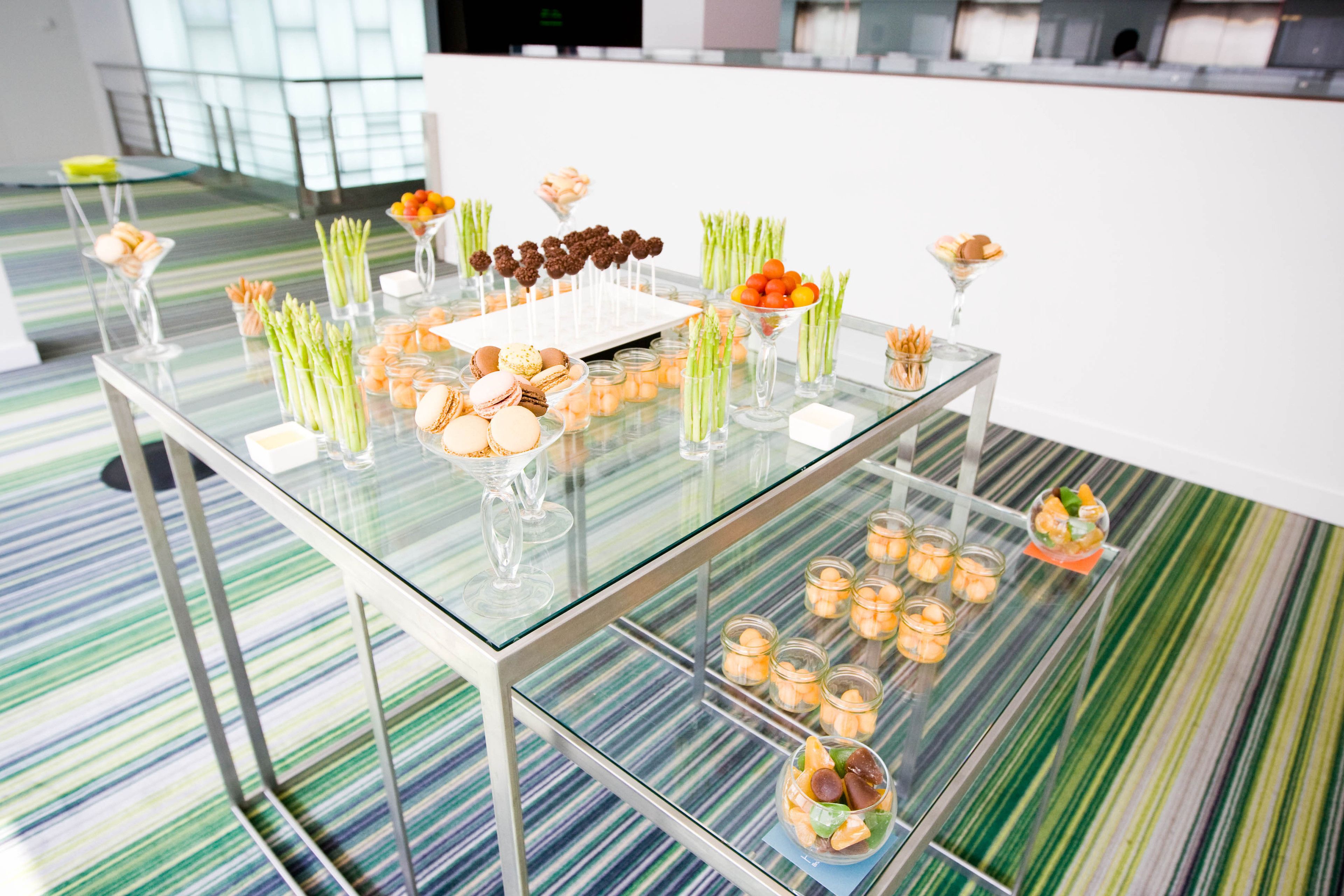 A glass-top table with various food items and candles, set on a striped floor.