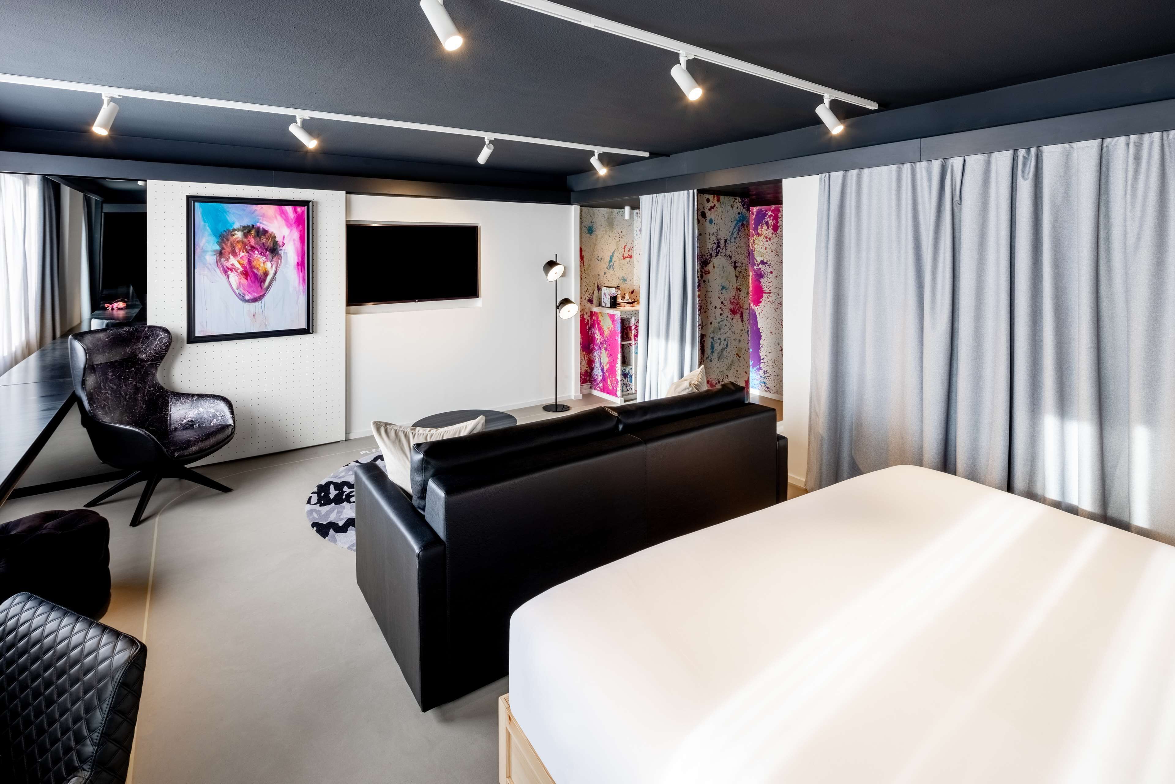 Una habitación de hotel moderna con una cama grande, un escritorio, una silla y un televisor.