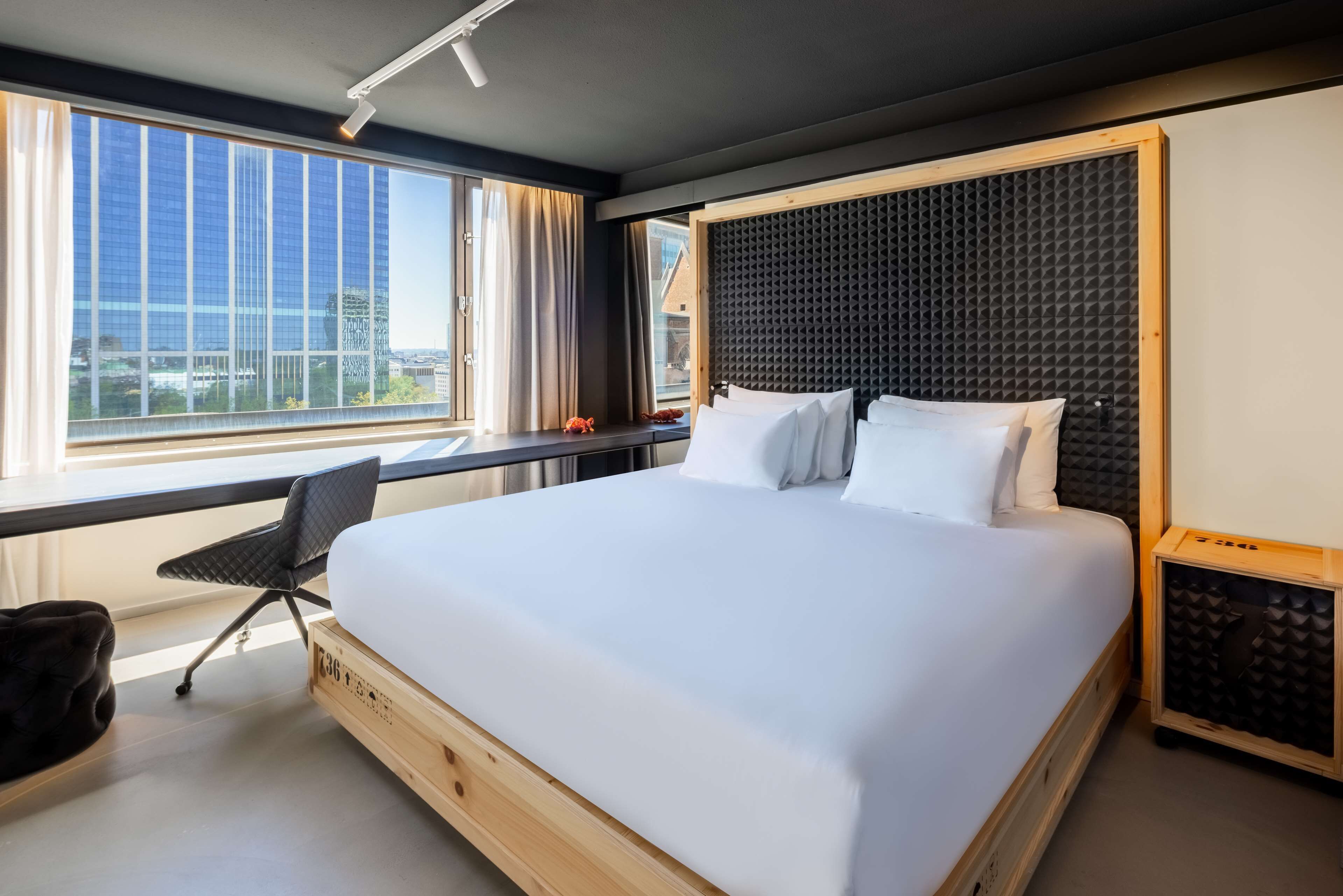 Habitación de hotel moderna con una cama grande, un escritorio y vistas a la ciudad.