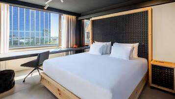 Habitación de hotel moderna con una cama grande, un escritorio y vistas a la ciudad.