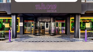 De ingang van nhow Hotels, met een draaideur en een modern design.
