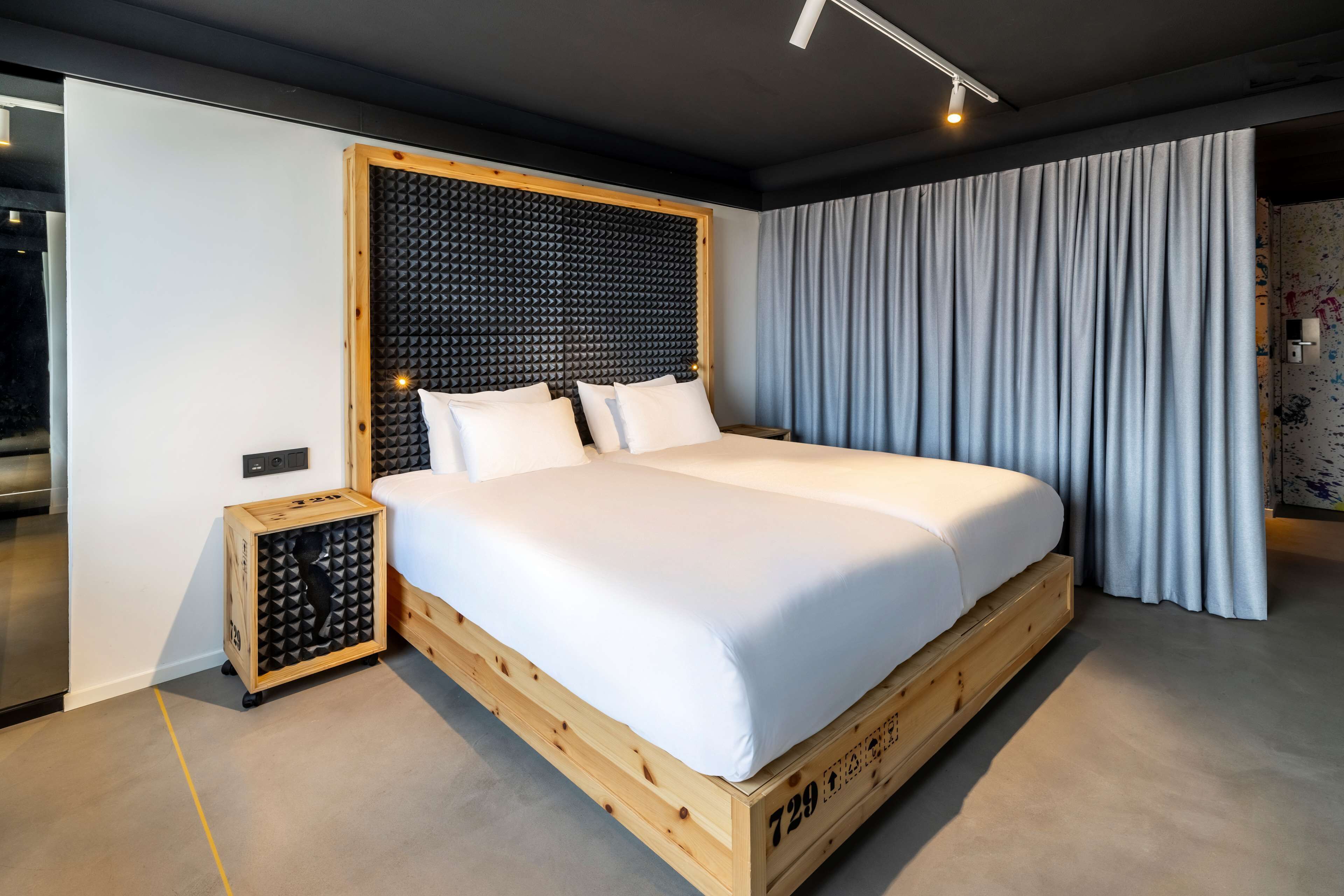 Un dormitorio moderno con una cama plataforma de madera, un cabecero insonorizado y un ventanal con cortinas.