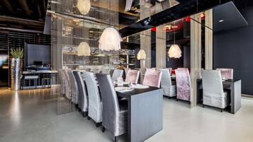 Un espace de salle à manger moderne avec une table centrale, des chaises à rayures et des luminaires suspendus.