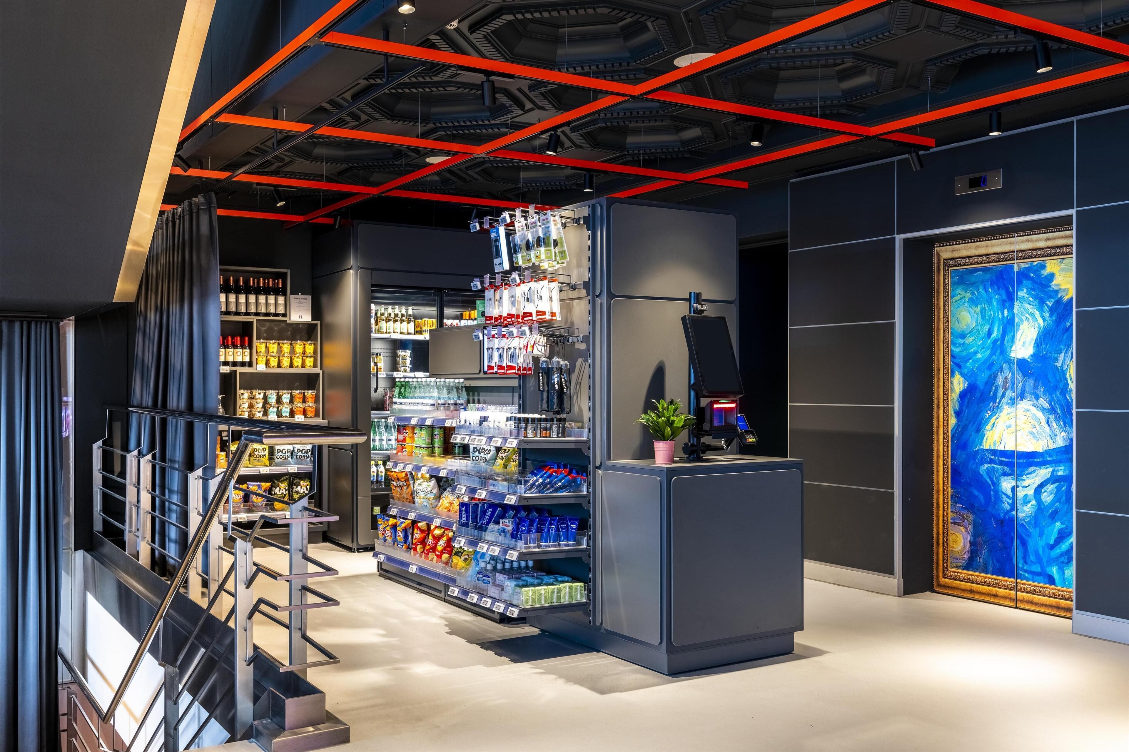 A modern retail space with shelves stocked with various products, a staircase, and a large painting on the wall.