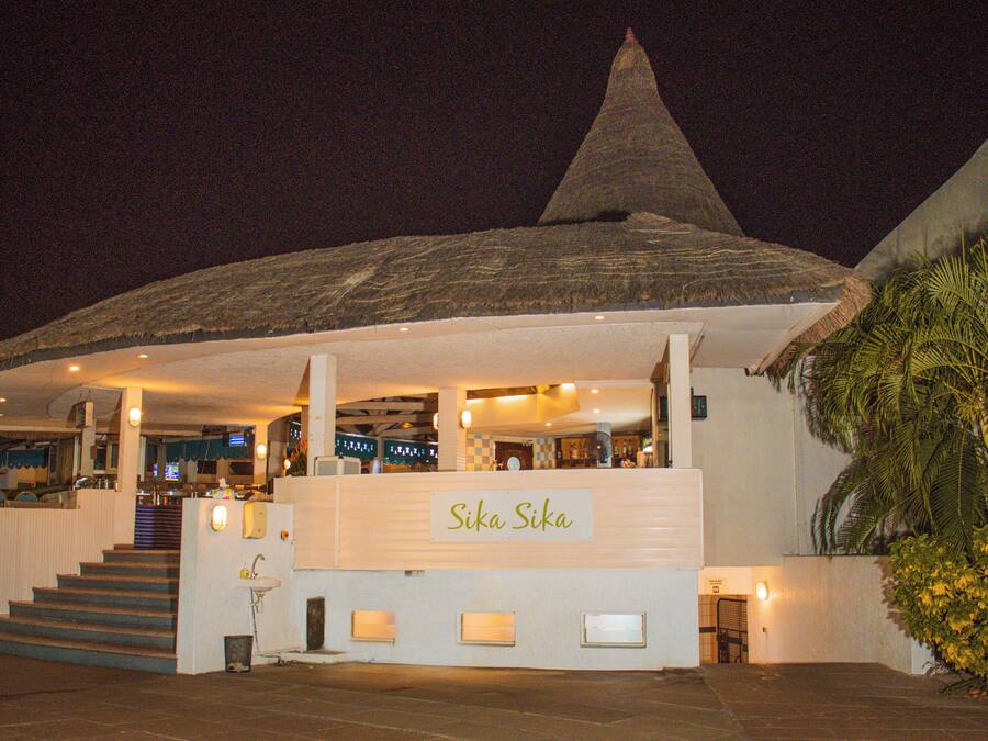 A building with a conical roof and a sign reading "Sika Sika".