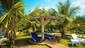 Un jardin tropical agrémenté de palmiers, d’un kiosque et de chaises longues.