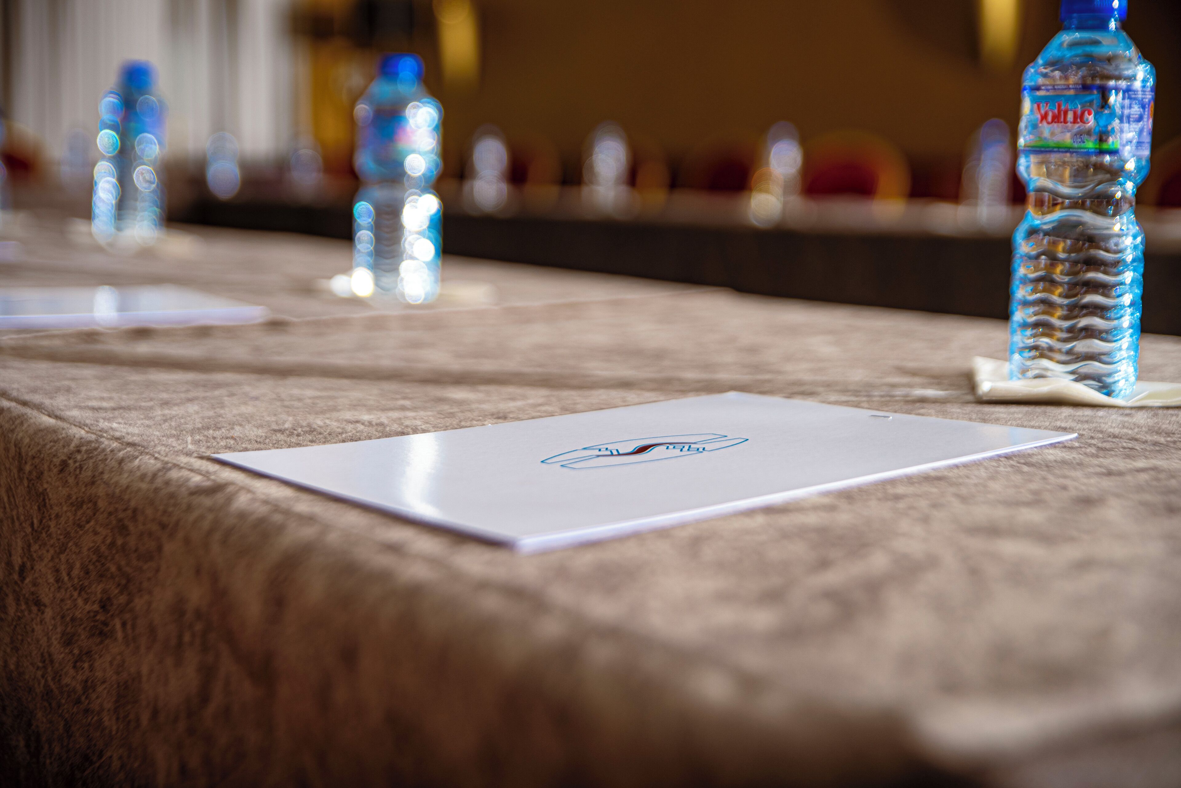 Una mesa de conferencias con botellas de agua y tarjetas de identificación.