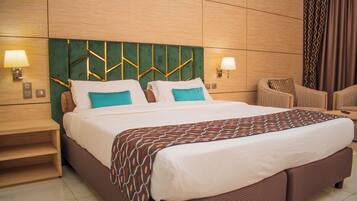 Ein Hotelzimmer mit einem großen Bett, zwei Nachttischen mit Lampen, einem Sessel und einer grünen Wand.