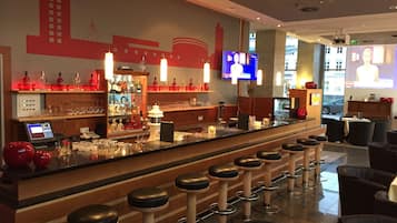 Eine Bar mit Hockstühlen, einer Theke und einem Fernsehbildschirm.