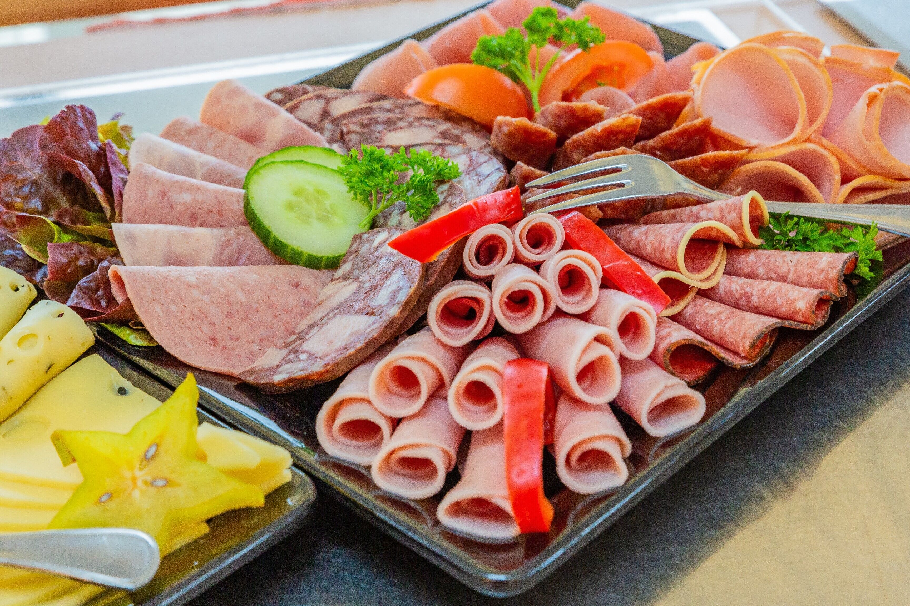 Une variété de charcuteries et de fromages coupés en tranches, présentés sur un plateau.