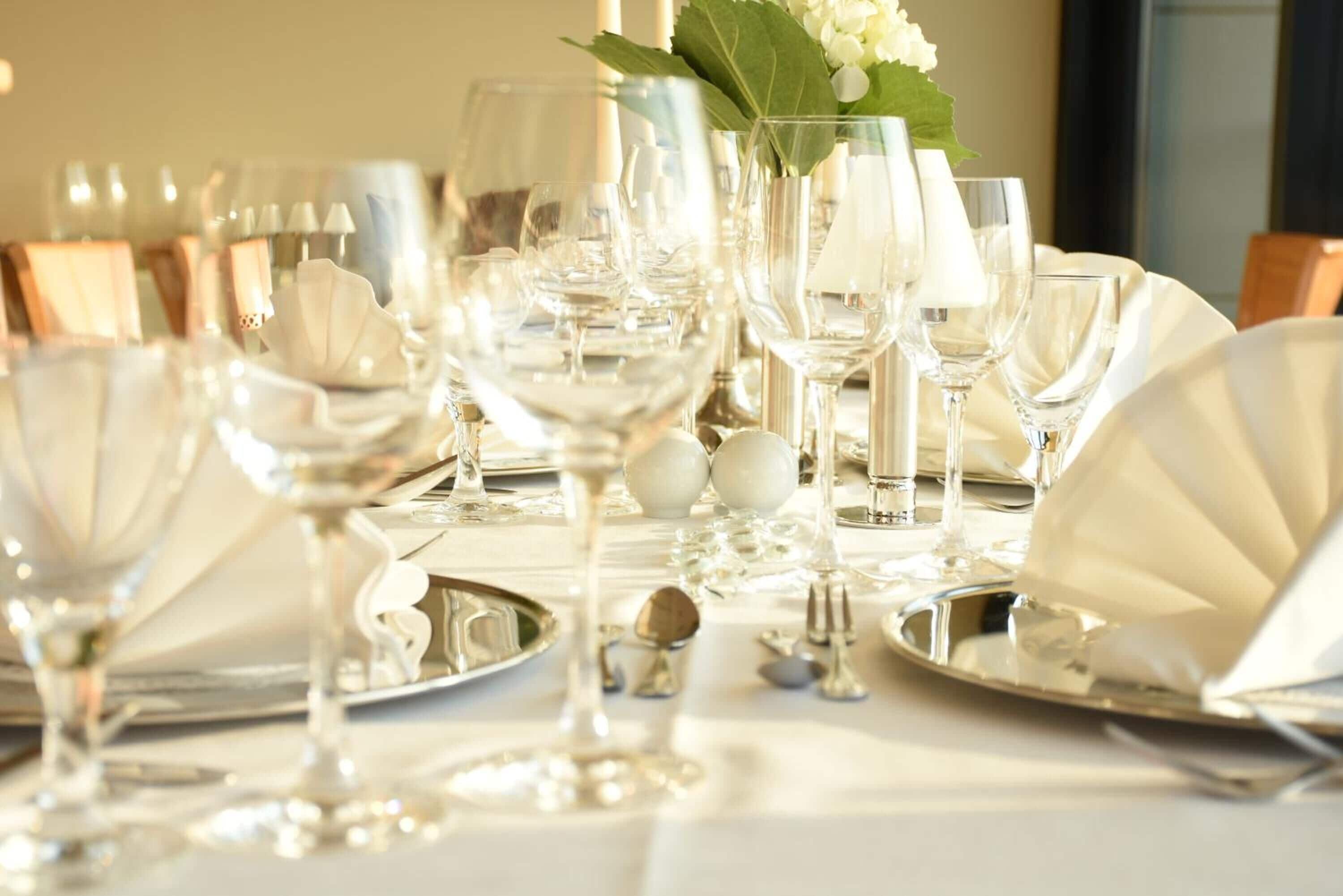 Una mesa dispuesta con varias copas de vino, platos y cubiertos, lo que sugiere un ambiente de comedor formal.