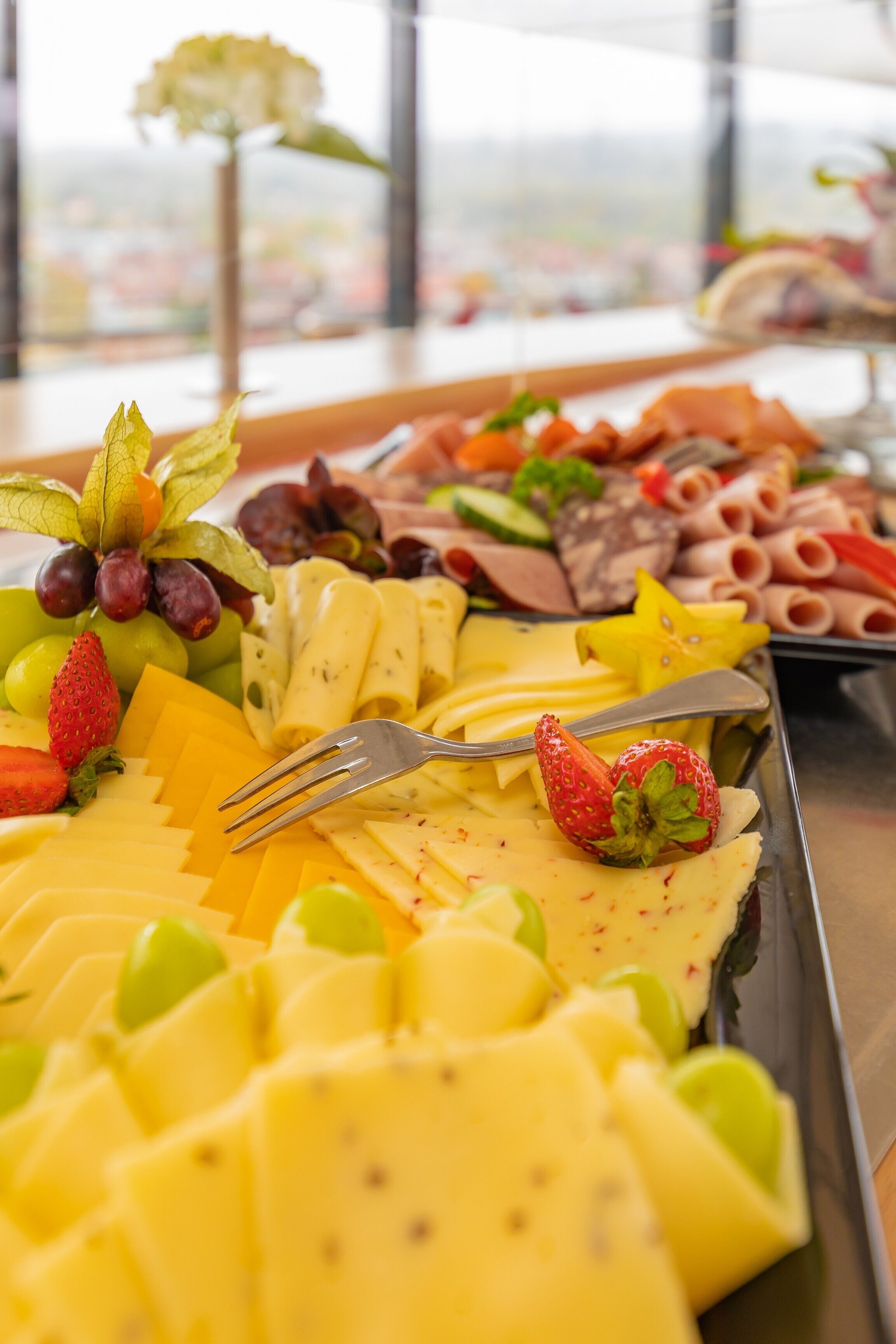 Un bufé con diversas frutas, quesos y embutidos.