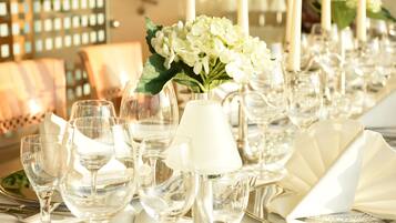 A table set with clear glassware, white napkins, and a vase of white flowers.