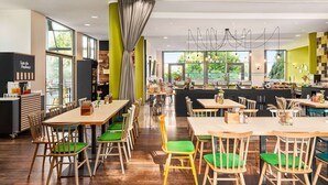 Un restaurante moderno con mesas y sillas de madera, ventanas amplias y un interior luminoso.