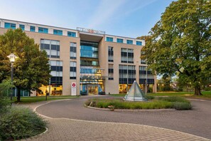 A modern hotel with a prominent entrance, glass facade, and a landscaped courtyard.