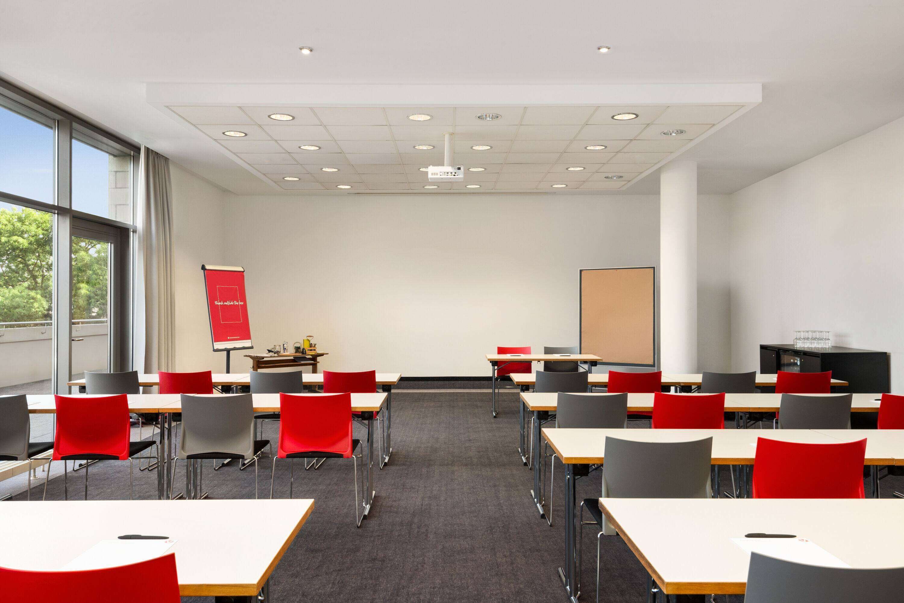 A conference room with tables and chairs, a projector, and a presentation screen.