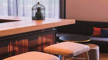 Un interior moderno con una barra de madera, taburetes acolchados, una mesa redonda y un sofá con cojines rojos y azules.