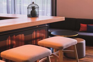 Un interior moderno con una barra de madera, taburetes acolchados, una mesa redonda y un sofá con cojines rojos y azules.