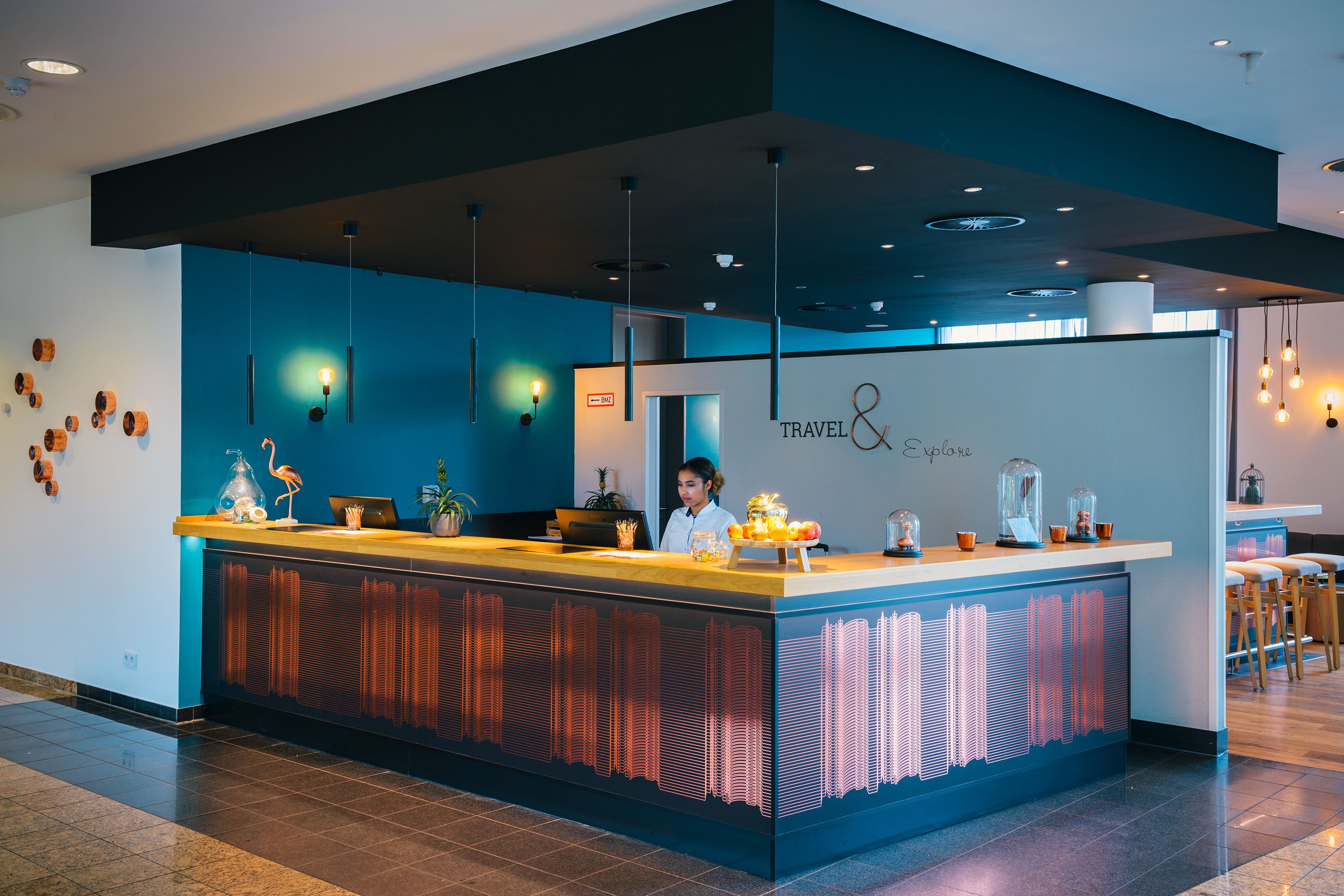 A modern reception desk with a blue and black color scheme, a digital display, and a bar area with stools.