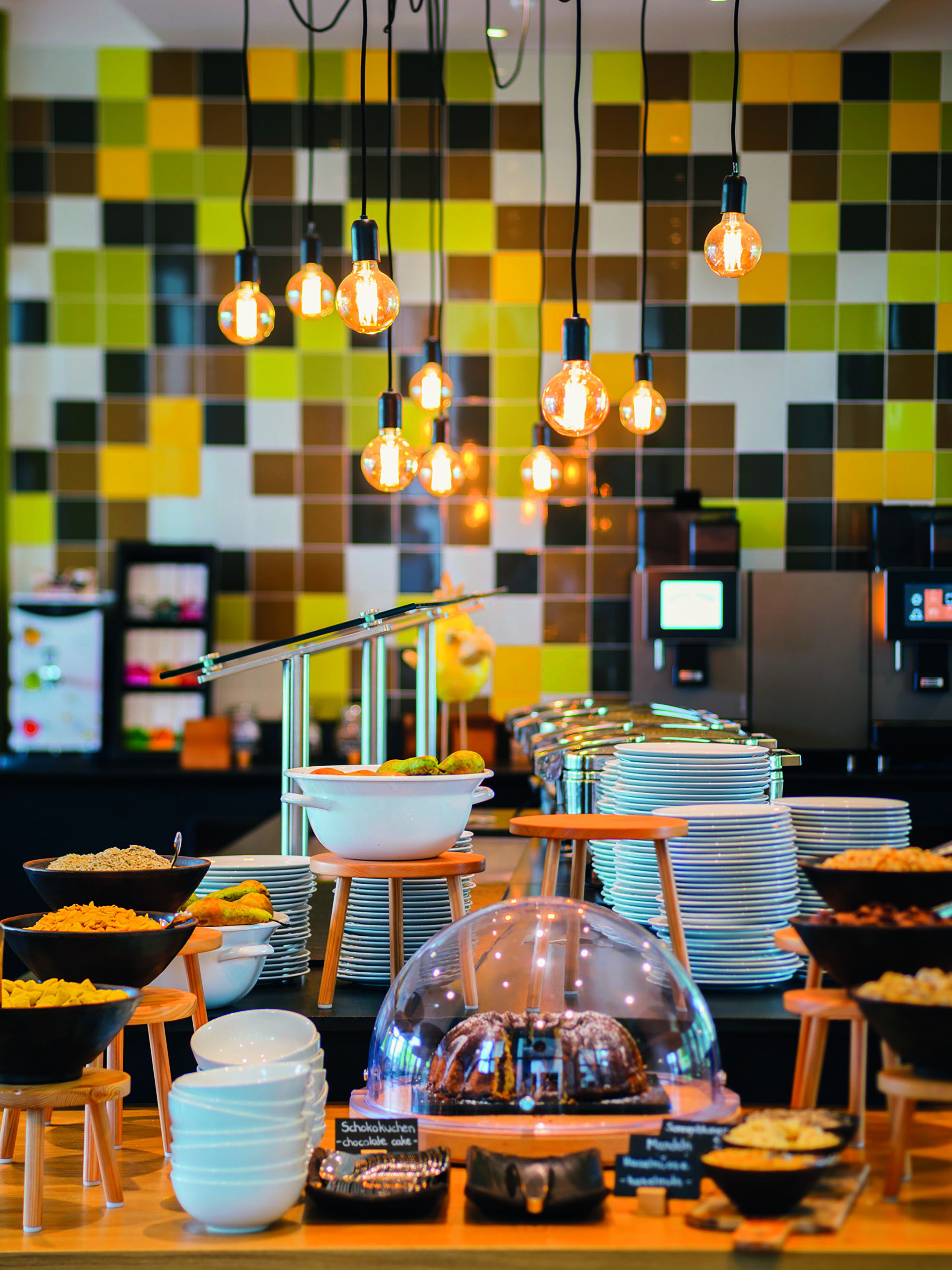 A buffet setup with various food items and a decorative chocolate cake under a glass dome.