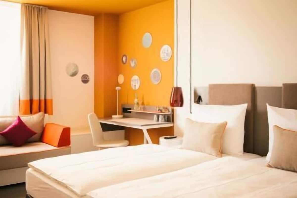 Una habitación de hotel con una cama, un escritorio y una silla.