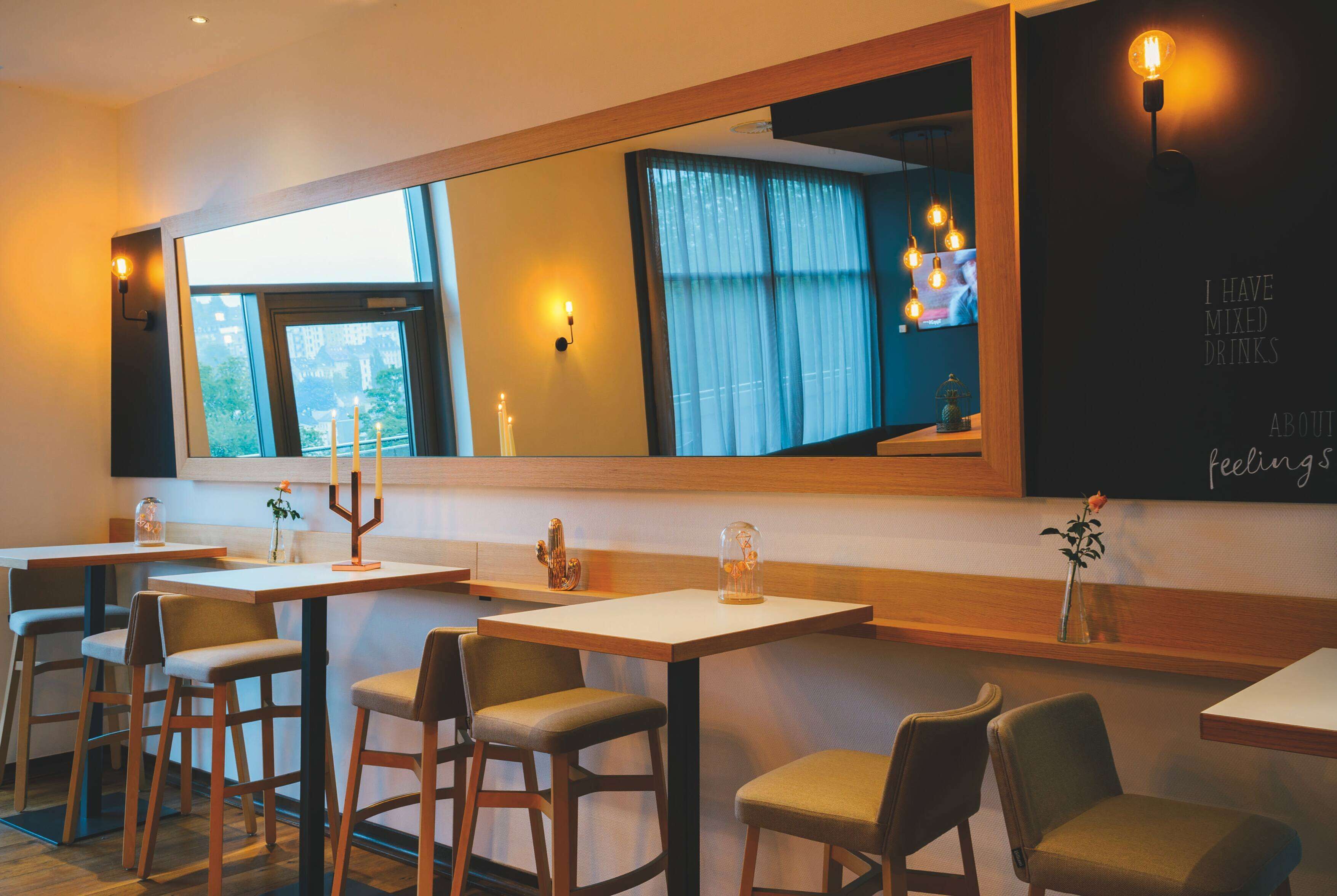 A restaurant with a large mirror, wooden tables, and chairs.