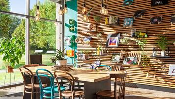 A modern cafe with a wooden slat wall, hanging light fixtures, and various plants.
