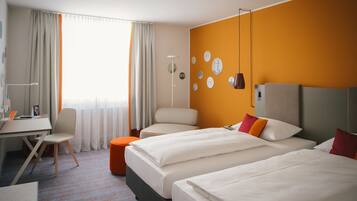 Habitación de hotel con dos camas, un escritorio, una silla y un amplio ventanal con cortinas.