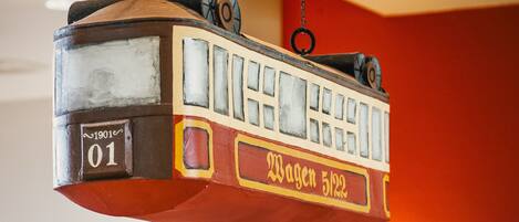 A vintage tram model with visible text and numbers, suspended from a chain.