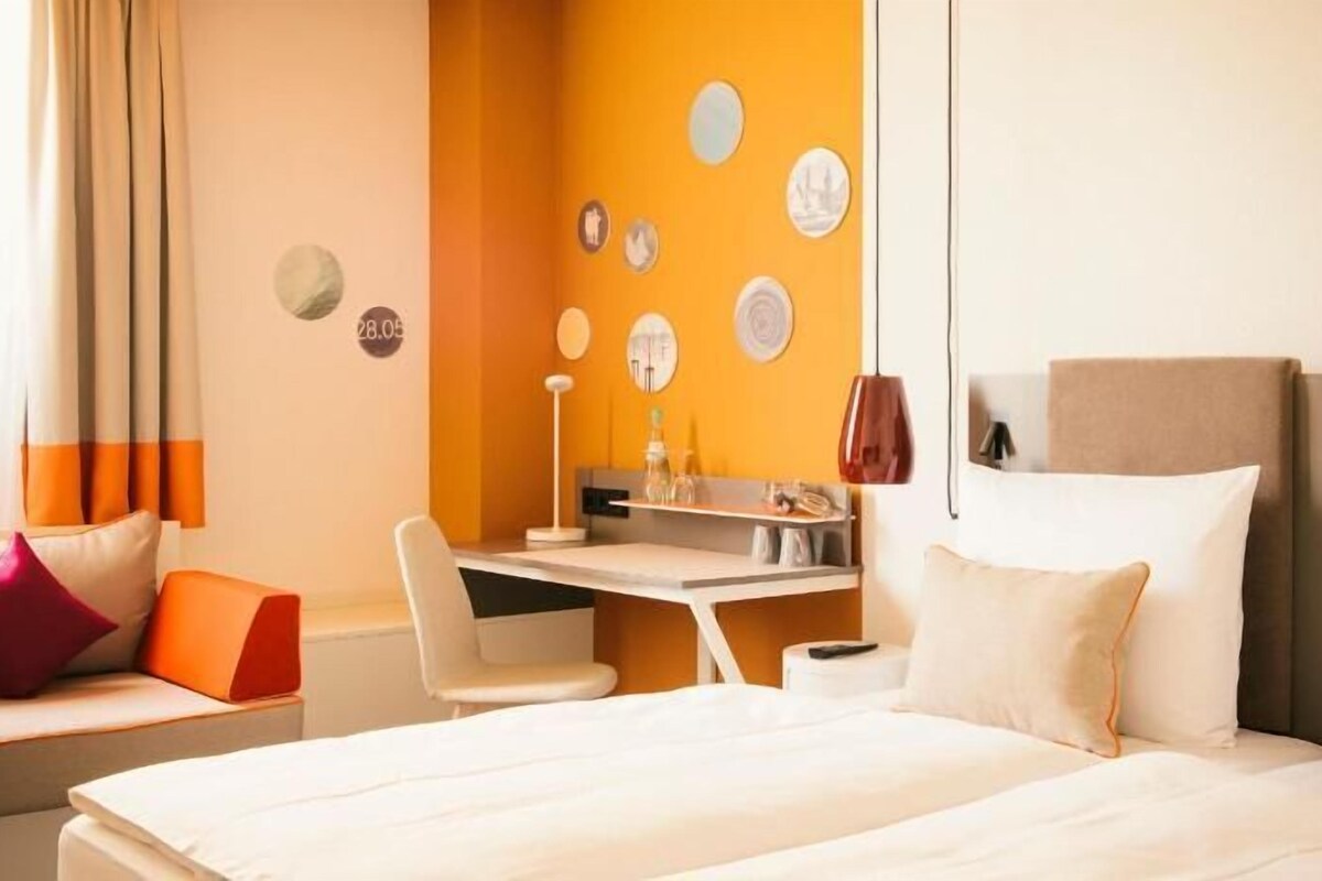 A hotel room with a bed, a desk, and a chair.