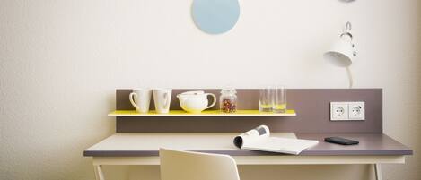 Una habitación moderna con un escritorio, una silla y una estantería con tazas, un hervidor y un tarro.