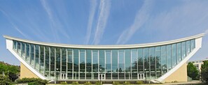 A modern building with a curved glass facade, large windows, and a white exterior.