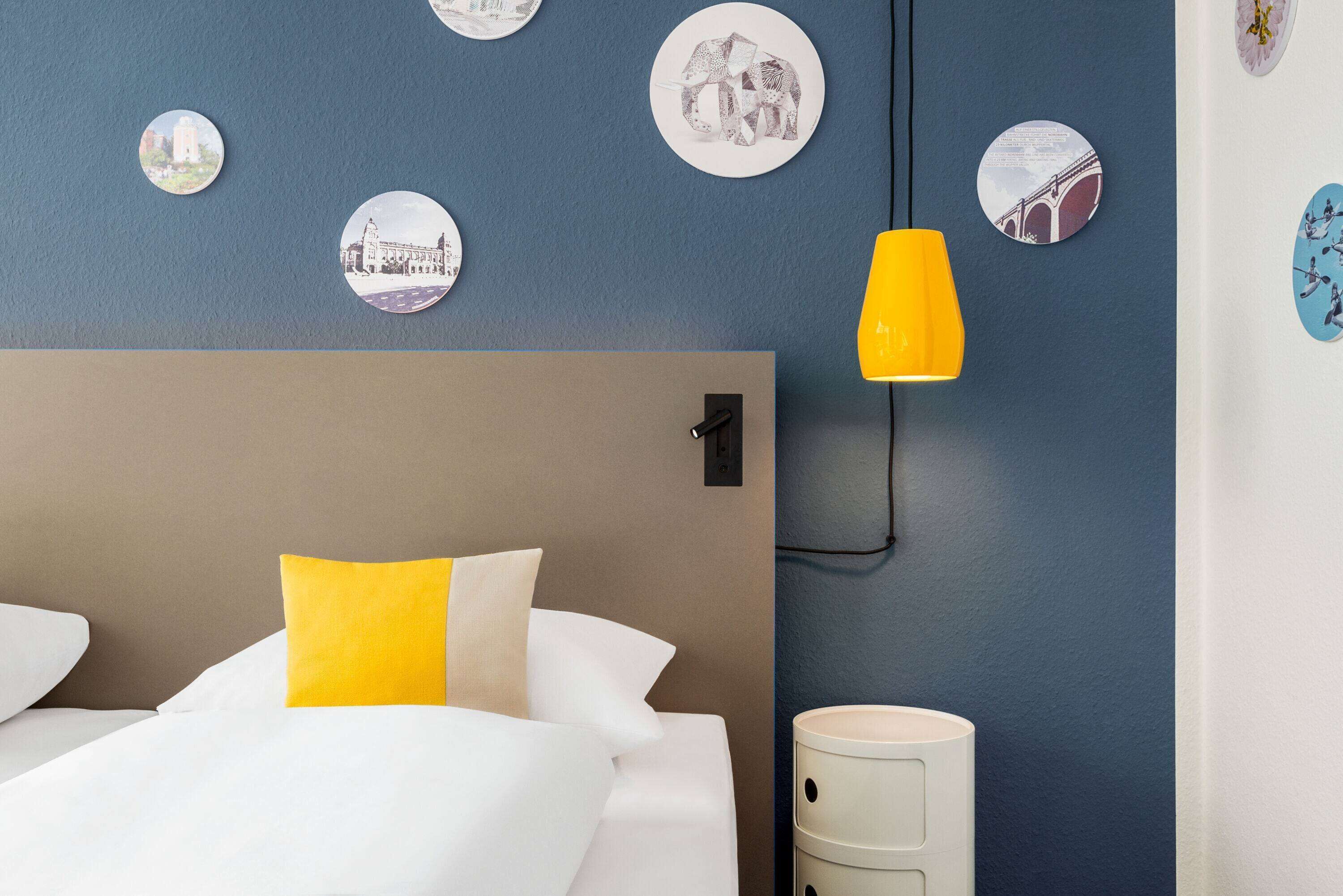 Ein Hotelzimmer mit Bett, Nachttisch, Lampe und Wanddekorationen.