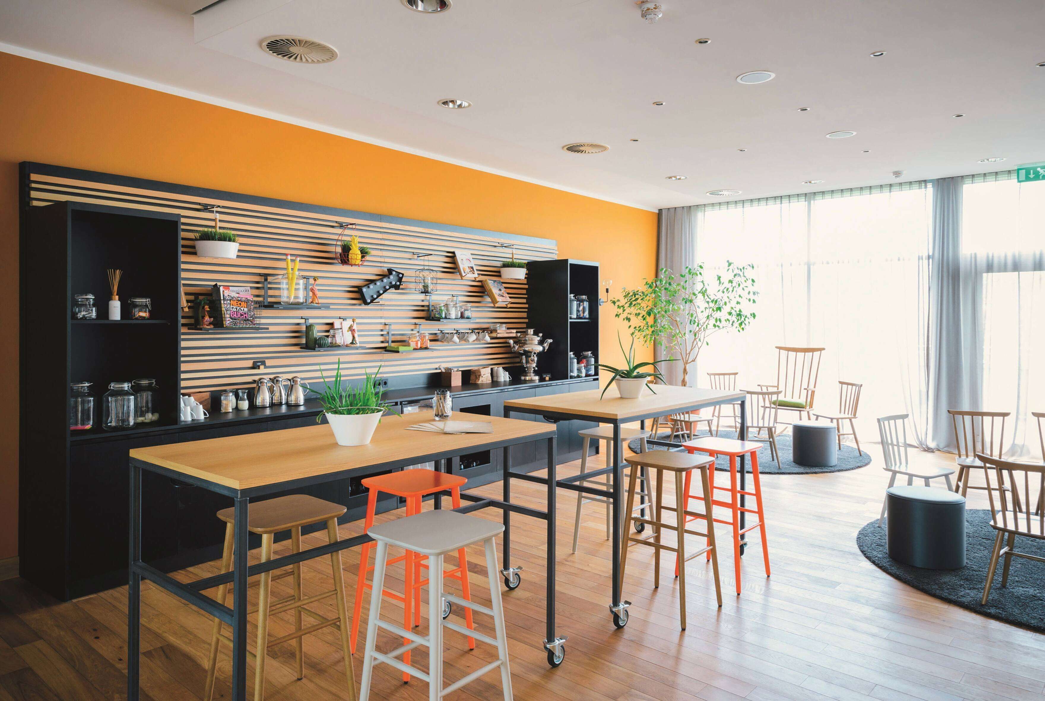 A modern kitchen with a wooden countertop, stools, and a wall-mounted rack with kitchen items.
