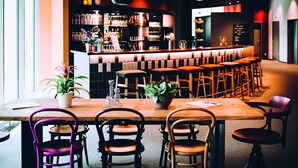 A bar area with a long counter, multiple stools, and a variety of bottles and glasses. - Vienna House Easy by Wyndham Trier (Trier)