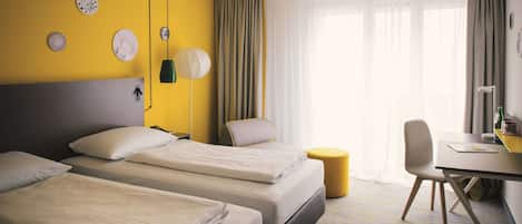 A hotel room with two beds, a desk, a chair, and a small round table.