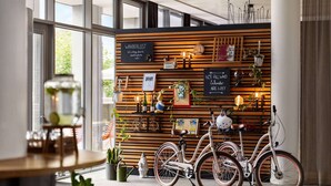 A modern interior with a wooden wall adorned with various items, including bicycles, plants, and framed pictures. - Vienna House Easy by Wyndham Trier (Trier)
