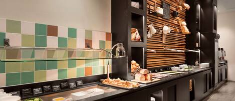 Montaje de bufé con diversos alimentos, una vitrina de vidrio y una pared con paneles de madera.