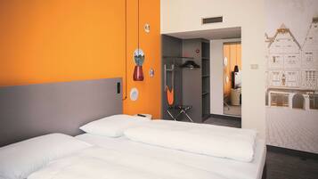 Une chambre d’hôtel comprenant un lit, une armoire, un miroir et un mur orné d’un motif décoratif.