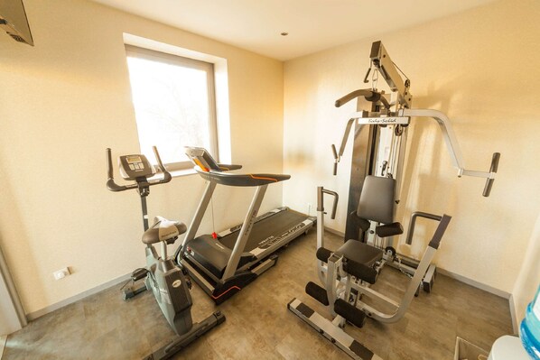 Un gimnasio en casa con cinta de correr, elíptica y máquina de pesas.