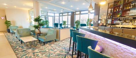 A modern hotel lobby with a bar area, seating, and large windows.